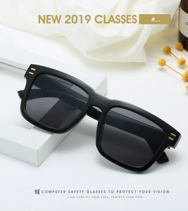 Detail view of matte black square frame sunglasses with golden hinge decorative accents