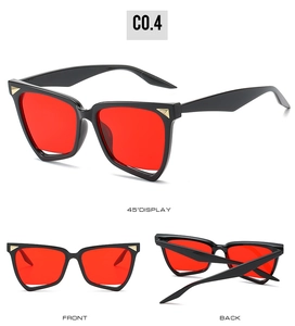Detailed view of irregular black sunglasses with red lenses and gold metal accents