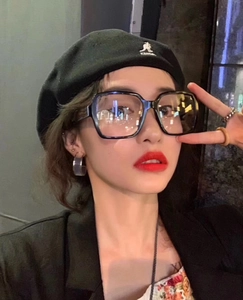 Close-up of black oversized square frame glasses on a model with a stylish beret