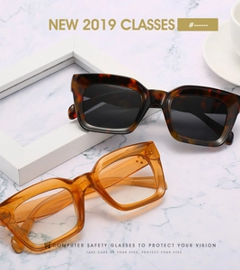 Détail de lunettes de soleil carrées en écaille avec rivets sur fond marbre