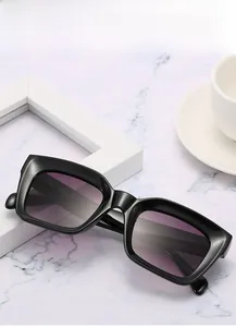 Détail de lunettes de soleil carrées en acétate noir avec verres dégradés violets sur marbre