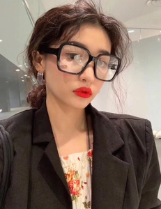 Close-up of a model wearing thick black square frame glasses with clear lenses