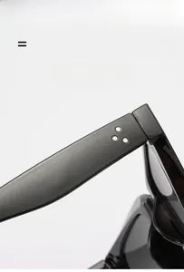 Détail de lunettes de soleil noires carrées avec trois rivets métalliques sur la branche