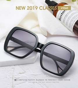 Close-up of square black sunglasses with gold metal triangle trim on marble stand