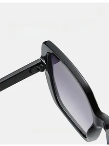 Detail of durable metal hinge on black oversized sunglasses with gray purple lenses