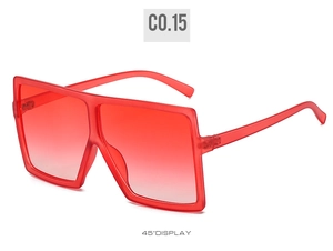 Detail view of oversized square sunglasses featuring translucent red frames and gradient lenses