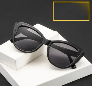Close-up of black cat-eye sunglasses with gray lenses on a white geometric block