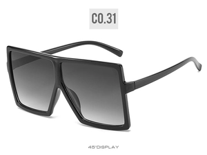 Three-quarter view of oversized square sunglasses with black frames and grey gradient lenses