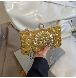 Close-up of golden evening bag with crystal flower pattern and pearl clasp detail
