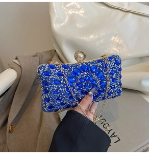 Close-up of luxury blue rhinestone clutch with gold chain strap and pearl clasp detail