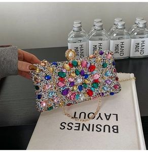 Detail of colorful gemstone inlay, faux pearl clasp, and gold chain on evening bag