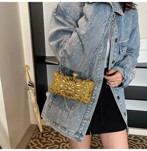 Detail of gold rhinestone evening bag with pearl clasp and chain worn with denim