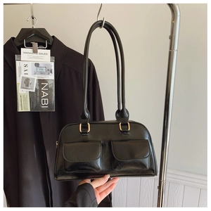 Detailed shot of black patent leather shoulder bag with dual front pockets and gold buckles