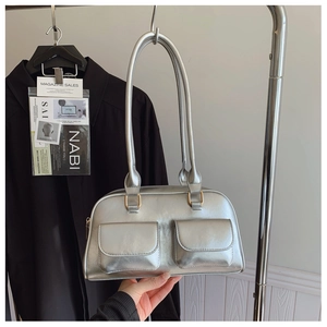 Detail of silver metallic handbag featuring dual front flap pockets and golden hardware