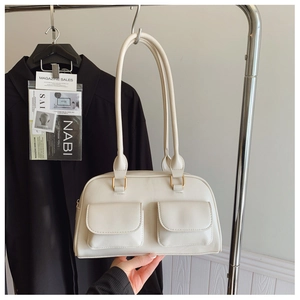 Detail of cream shoulder bag with dual front pockets and premium gold hardware