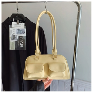 Detail of buttery yellow shoulder bag with double front flap pockets and slim straps