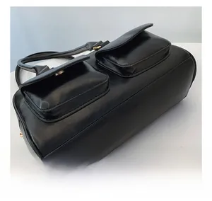 Detail shot of black minimalist bowling bag showing glossy leather texture and gold buckles