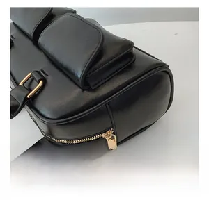 Close-up of smooth gold zipper and buckle hardware on black PU leather handbag