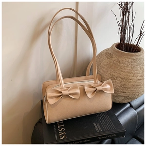 Detailed view of beige faux leather shoulder bag featuring decorative double bows on front