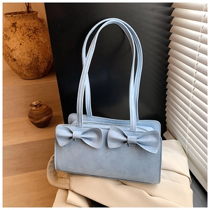 Detail of light blue bow handbag with matte leather texture and metal zipper closure
