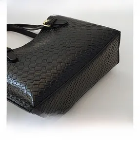 Close-up of black woven texture on leather bag with gold metal hardware detail