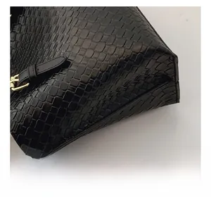 Detail view of black embossed leather bag with gold buckle and fine stitching