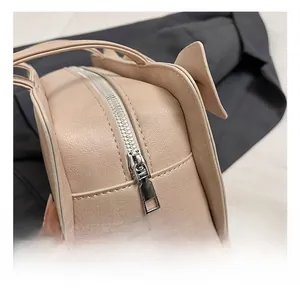 Close-up of sleek silver zipper hardware on a nude textured leather handbag detail