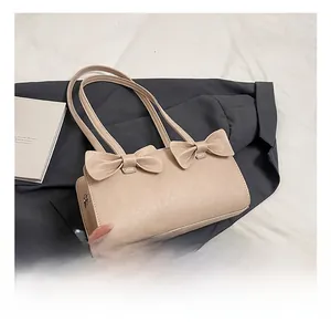 Detail show of a beige handbag featuring decorative double bows and elegant twin handles