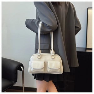 Detail of off-white Boston bag with dual front flap pockets and golden hardware accents