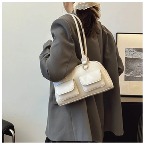 Detail of white Boston bag with two front flap pockets and golden hardware on shoulder