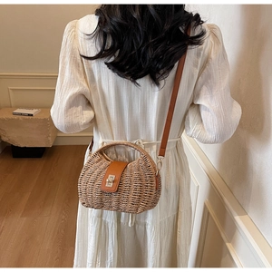 Detail of hand-woven straw bag with brown leather flap and silver twist lock on white dress