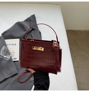 Detail of burgundy crocodile-embossed Kelly bag with gold hardware and top handle
