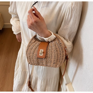 Detailed close-up of woven straw saddle bag with brown leather flap and gold twist lock