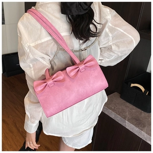 Pink bow-adorned shoulder bag shown on model for size perspective and sweet style