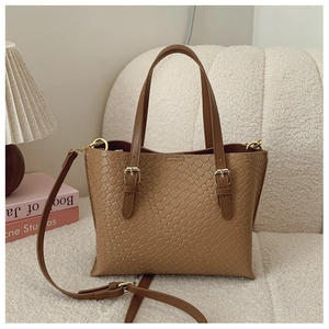 Detailed view of brown woven texture and gold metal buckle on a designer tote bag