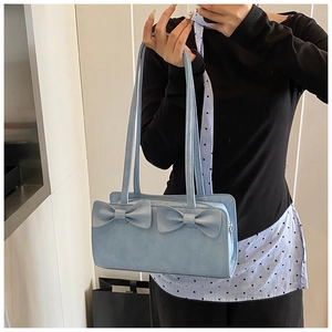 Close-up of a light blue bow-accented handbag with soft matte texture and shoulder strap