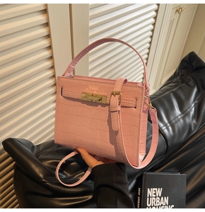 Pink crocodile-embossed handbag featuring gold buckle details and adjustable shoulder strap
