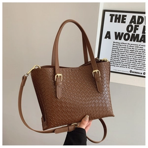Detail of caramel brown woven texture shoulder bag with golden metallic hardware accents