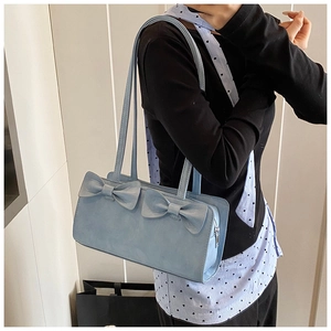 Light blue crossbody bag with bow details shown on a model for size and style reference