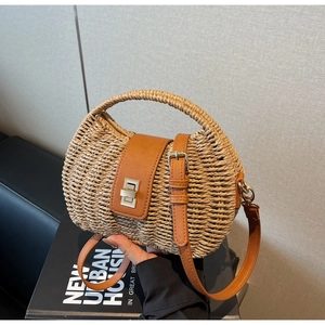 Detail of hand-woven straw handbag featuring premium brown leather handle and metal lock