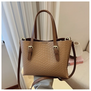 Macro detail of brown woven leather texture and gold buckles on a chic shoulder bag