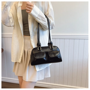 Detail of minimalist black PU leather Boston bag with functional pockets and long straps