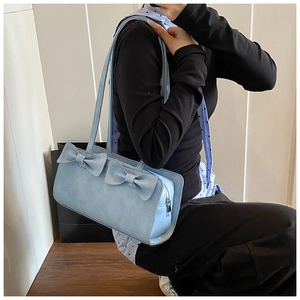 Detail of light blue faux suede baguette bag featuring decorative twin bows and silver zipper