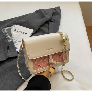 Detail of cream leather crossbody bag with pink woven panel and gold chain strap