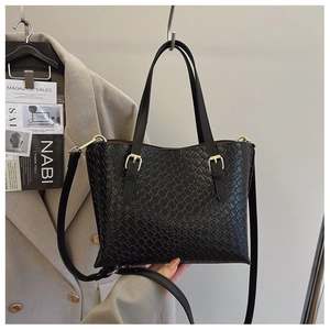 Detail of black woven texture underarm bag with gold hardware and removable shoulder strap