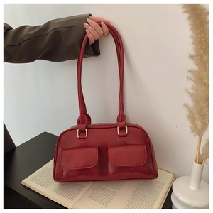 Detail of red leather Boston bag with double front pockets and gold hardware accents