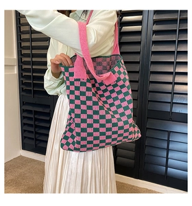 Gros plan du sac cabas en maille damier rose et vert porté par un mannequin en tenue décontractée
