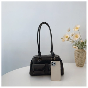 Minimalist black leather Boston bag on a table with a smartphone for size reference