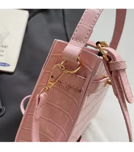 Detail of pink croc-embossed bag featuring shiny gold-tone metal hardware and leather texture