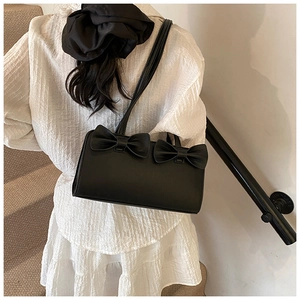 Detail view of a black bow handbag featuring a dual strap design and matte finish material